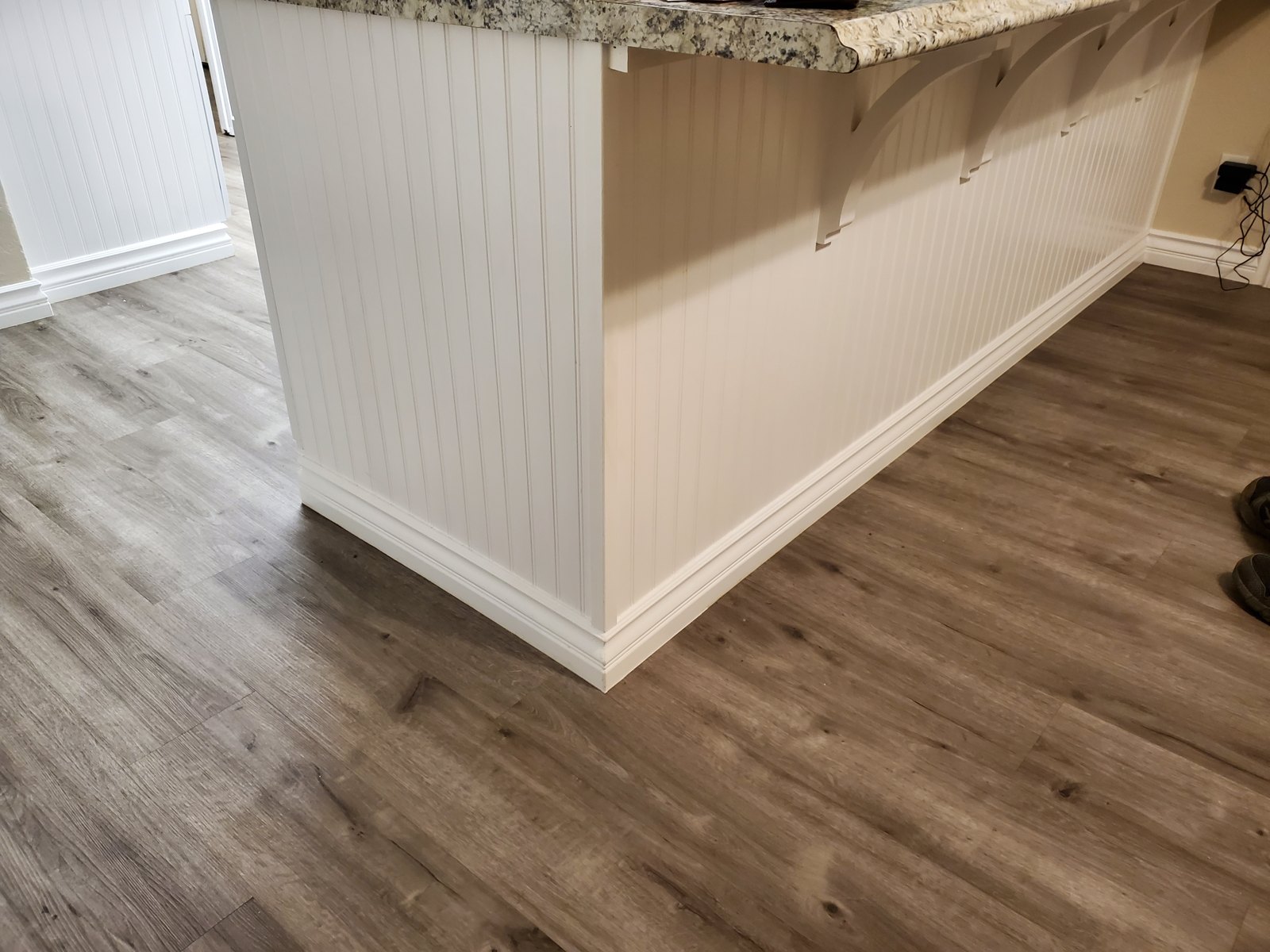 Beadboard island panel with new baseboard and luxury vinyl plank flooring