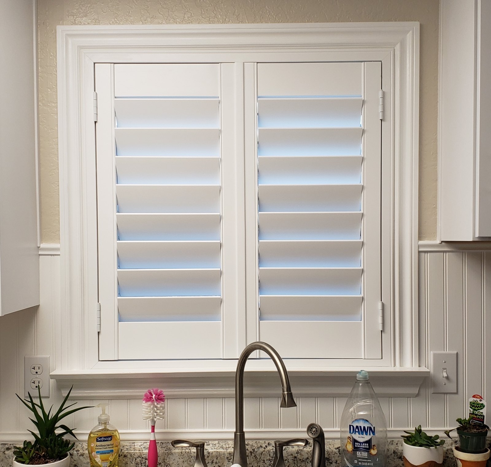 Custom window casing with plantation shutters over a kitchen sink