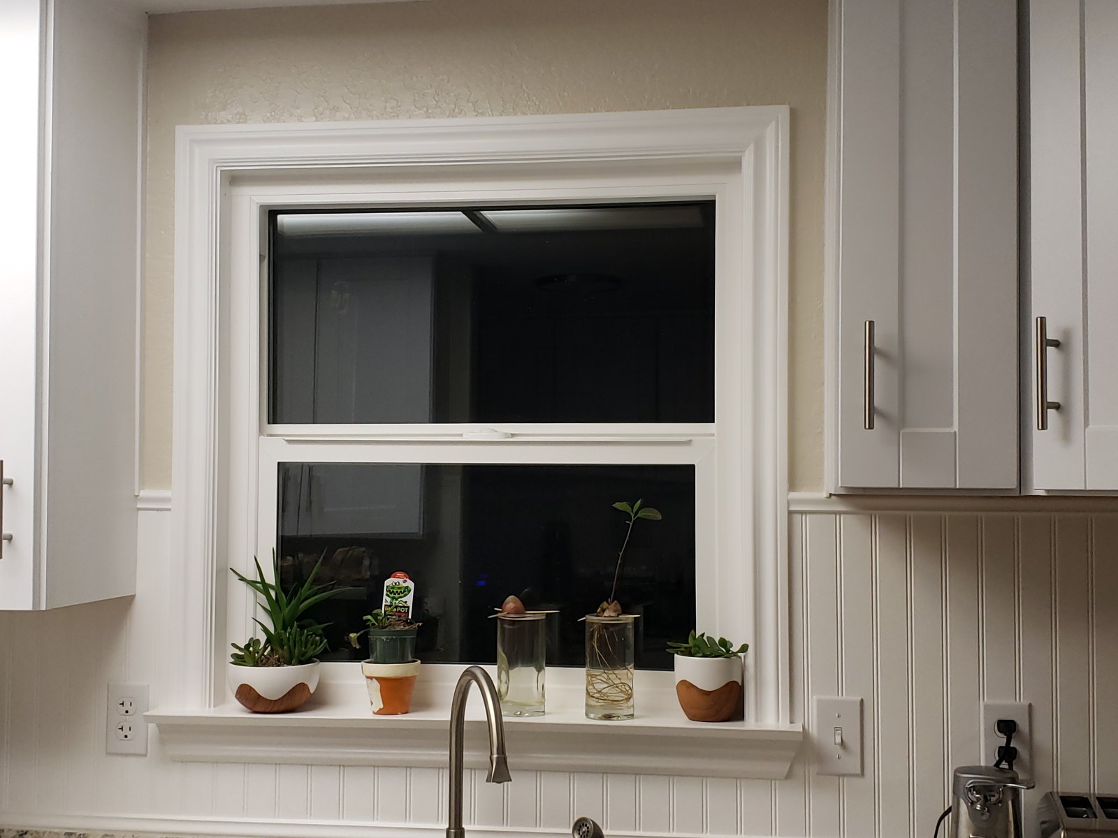 Kitchen with beadboard backsplash, white cabinets and custom window casing